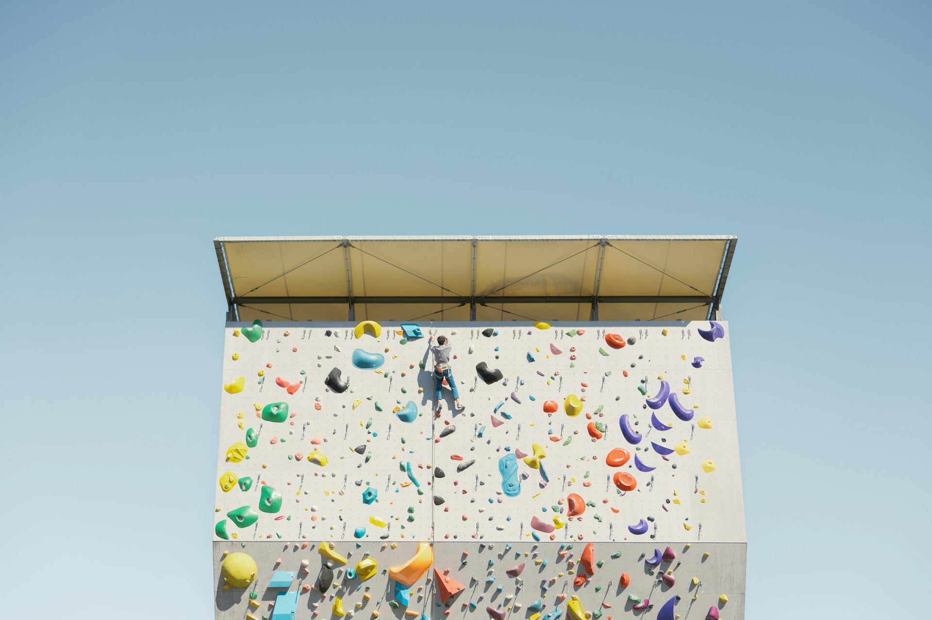 Person climbing a colorful outdoor bouldering wall.